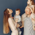 Portrait of a joyful family with parents and kids showing love and affection against a blue background.